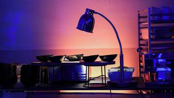 A kitchen with a blue lamp, a metal rack, and a bowl of greens.