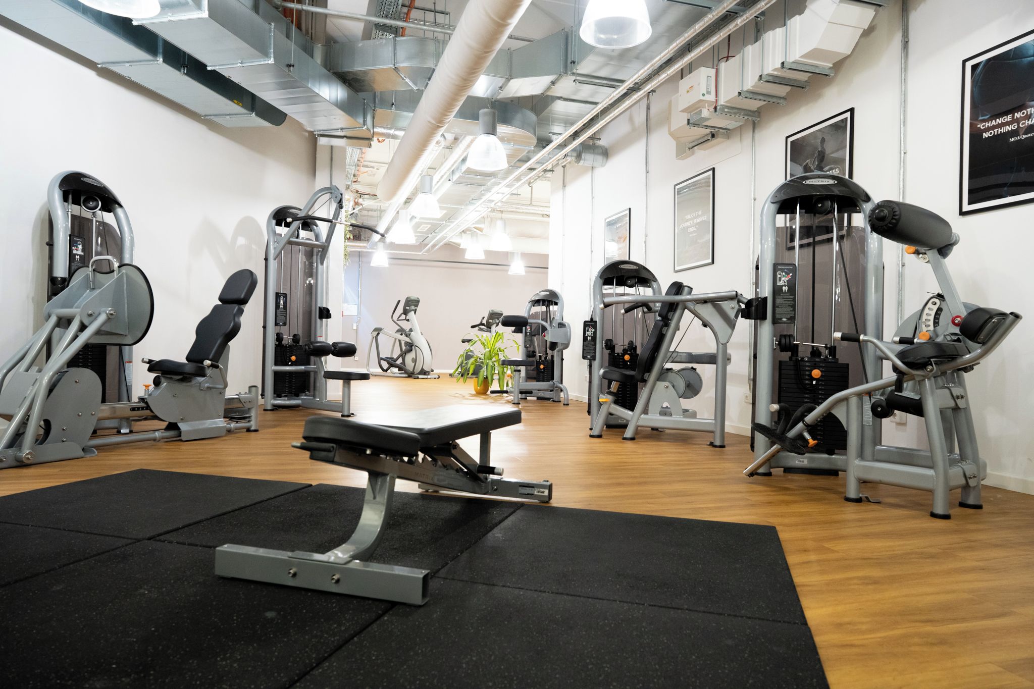 Un gimnasio con diferentes máquinas de ejercicio, una banca y un espejo.