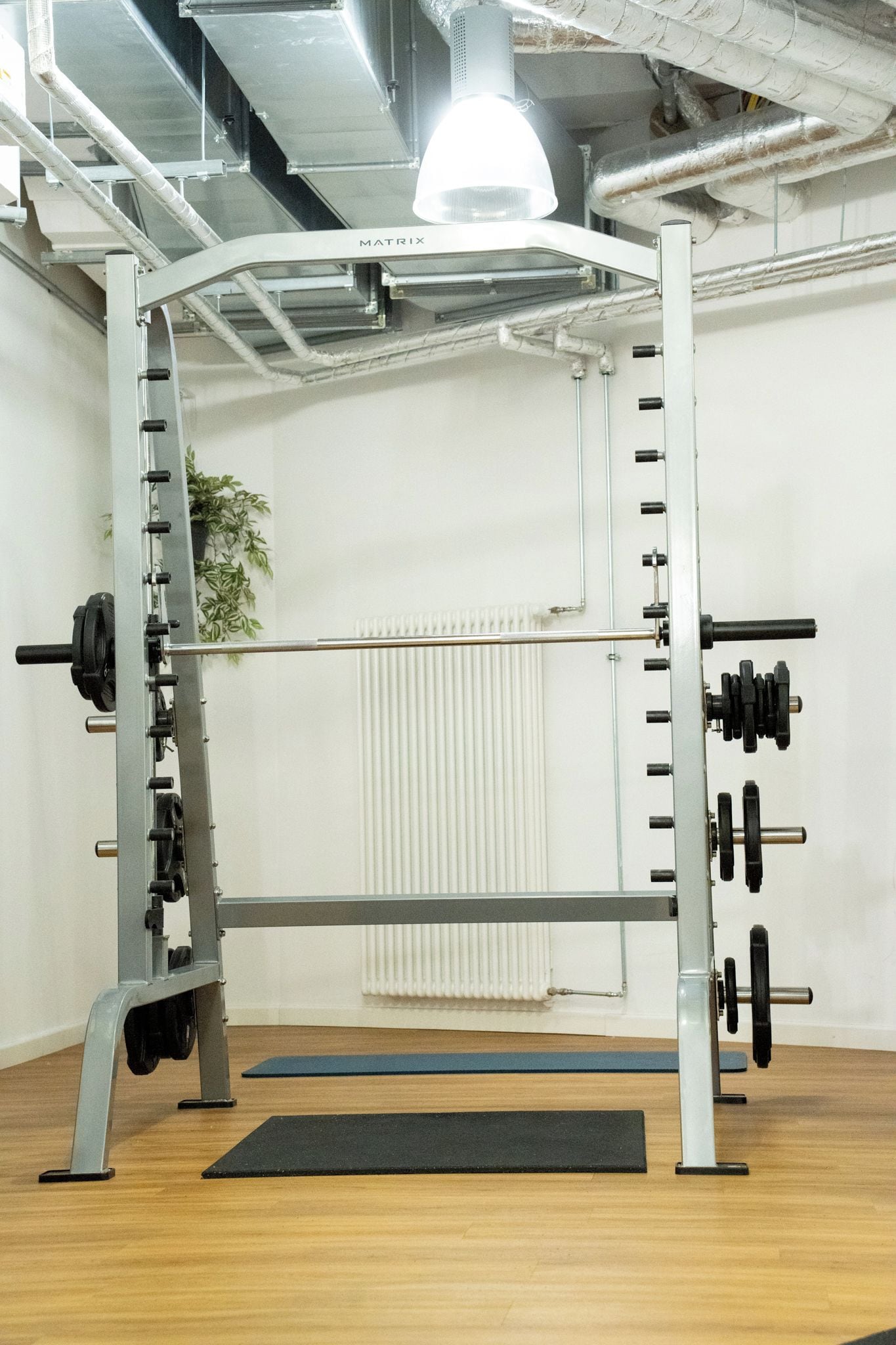 A gym with a weightlifting rack, a mat, and a radiator.