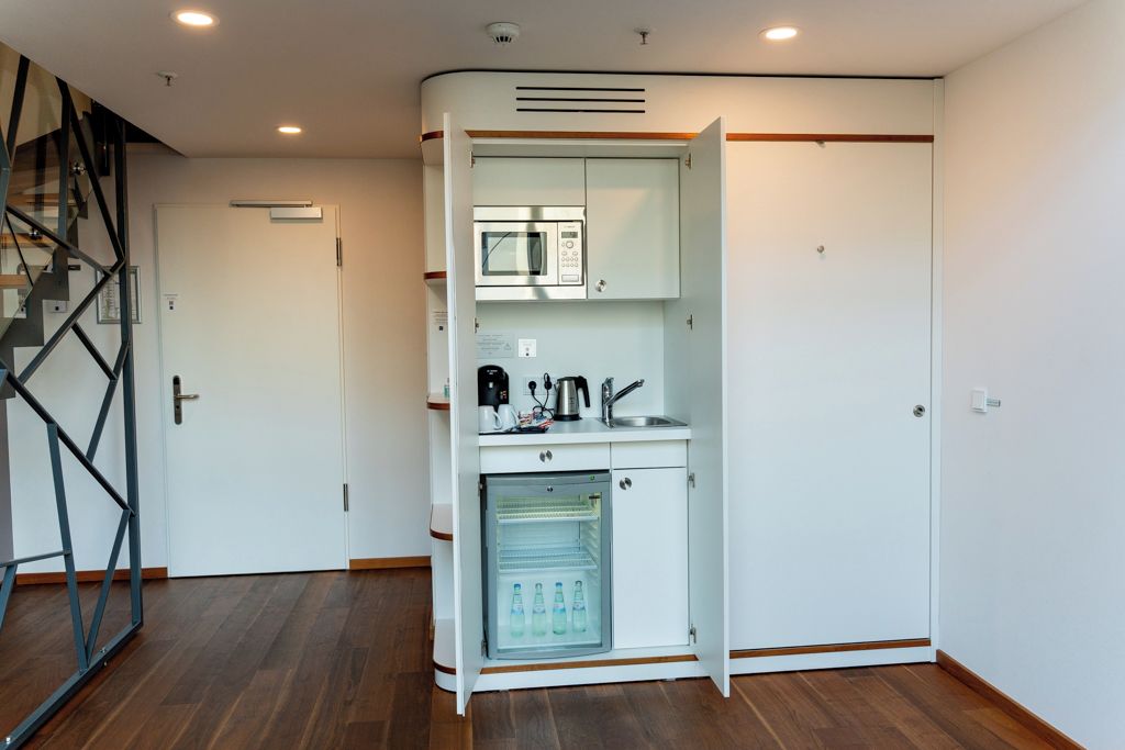 Uma cozinha compacta equipada com micro-ondas, cafeteira e mini-geladeira.