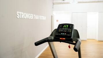 Ein Laufband in einem Raum mit einem motivierenden Wandspruch und einem digitalen Display.