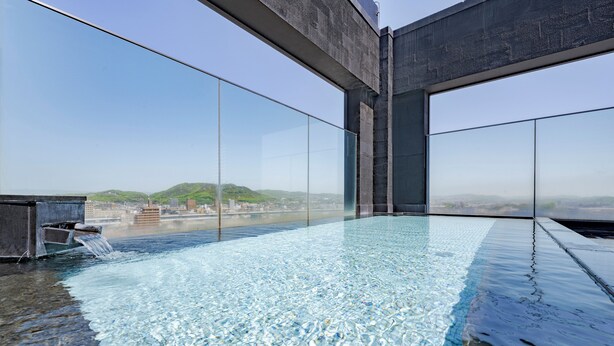 Una piscina infinita moderna con vistas despejadas al paisaje urbano y colinas al fondo.