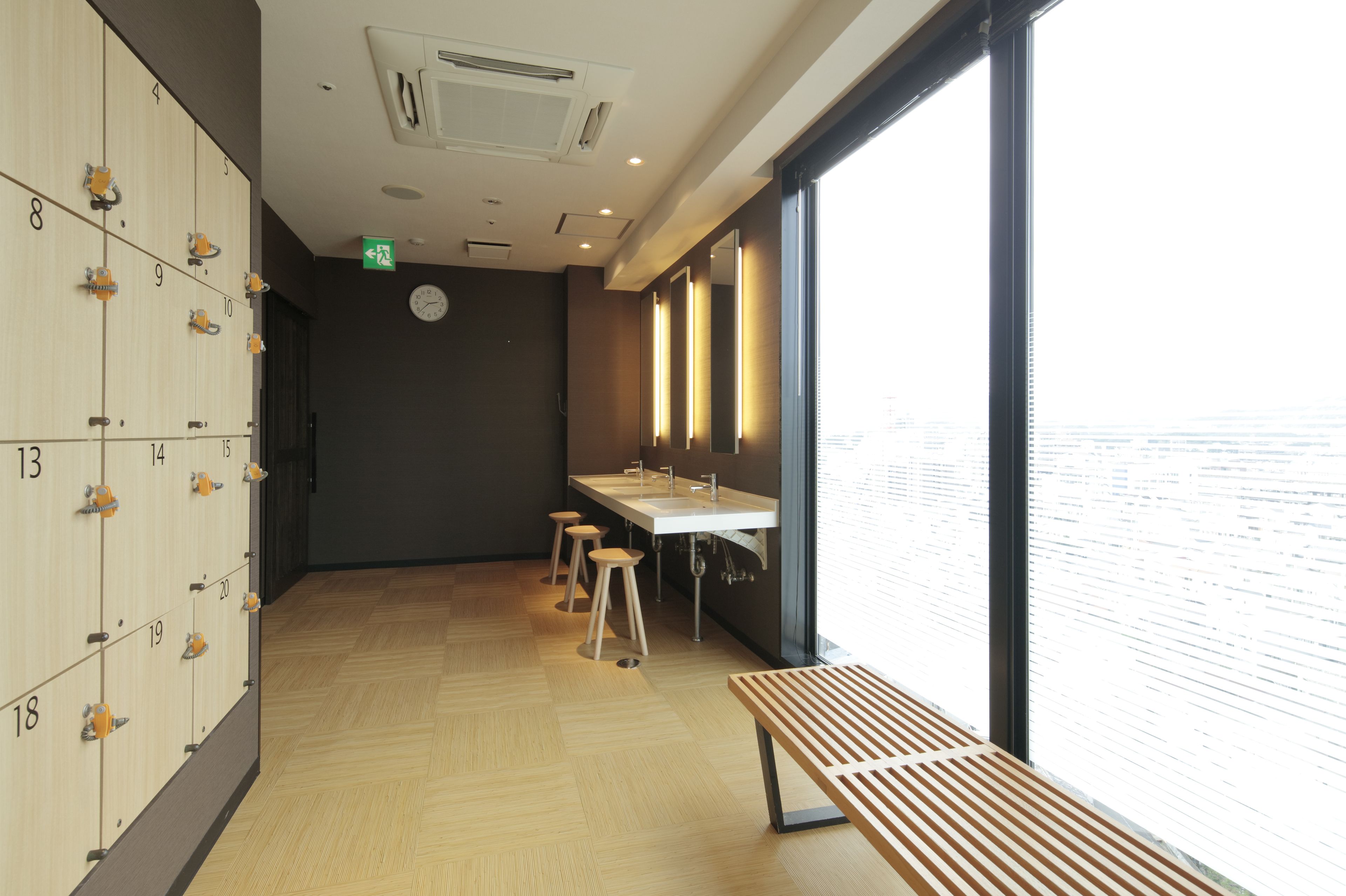 A modern bathroom with lockers, a bench, and a large window providing a view.