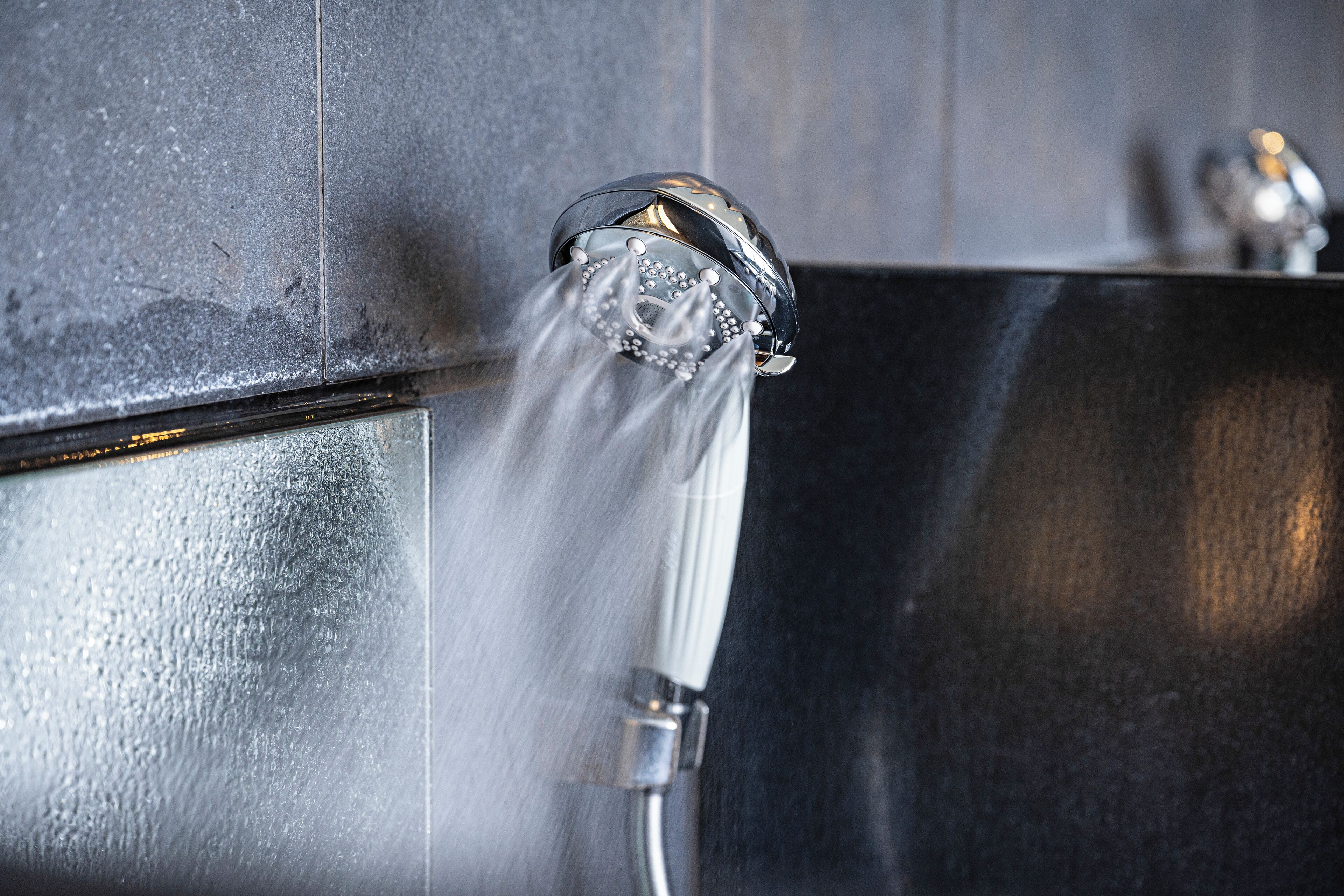 A shower head with water flowing from it.