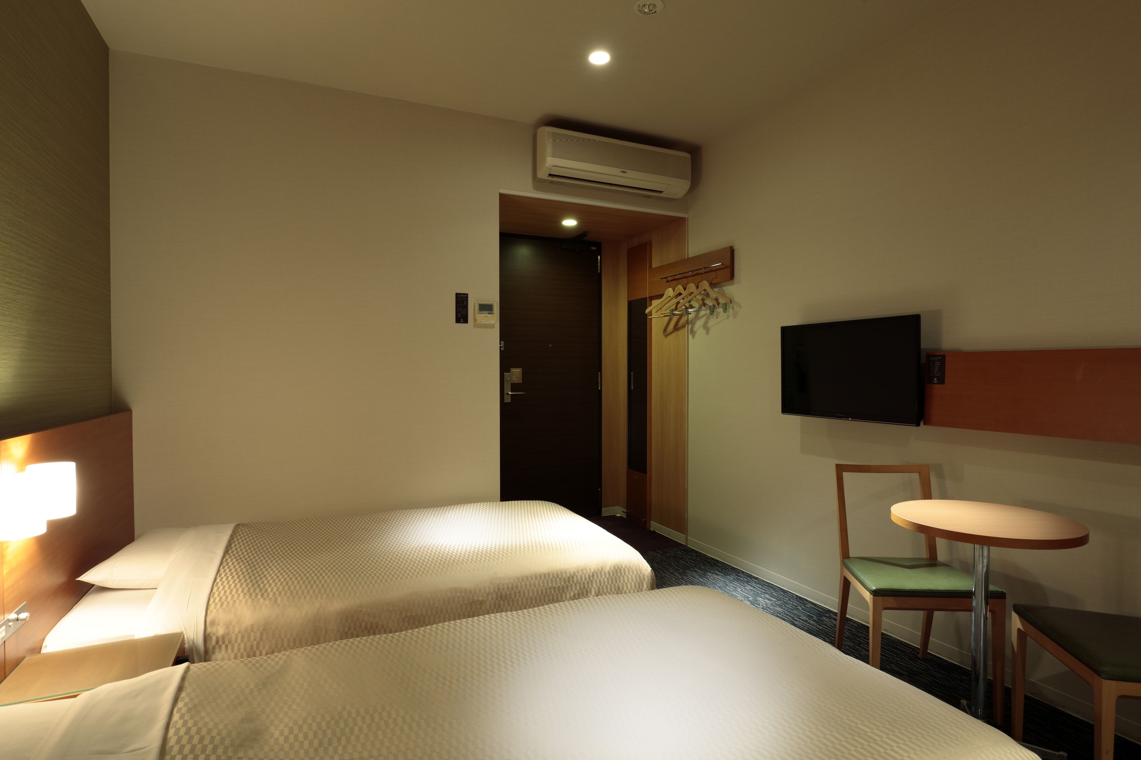 Une chambre d’hôtel avec deux lits, une télévision, une petite table et une chaise.