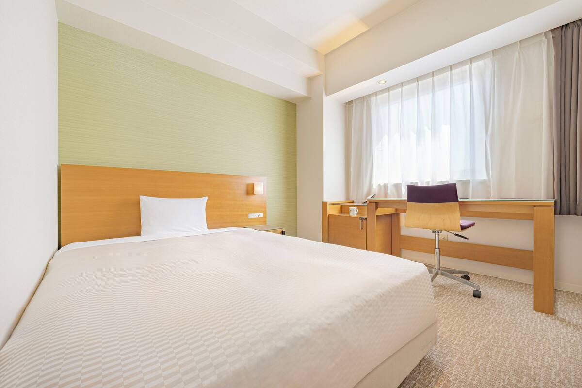 Een hotelkamer met een groot bed, een bureau en een stoel.