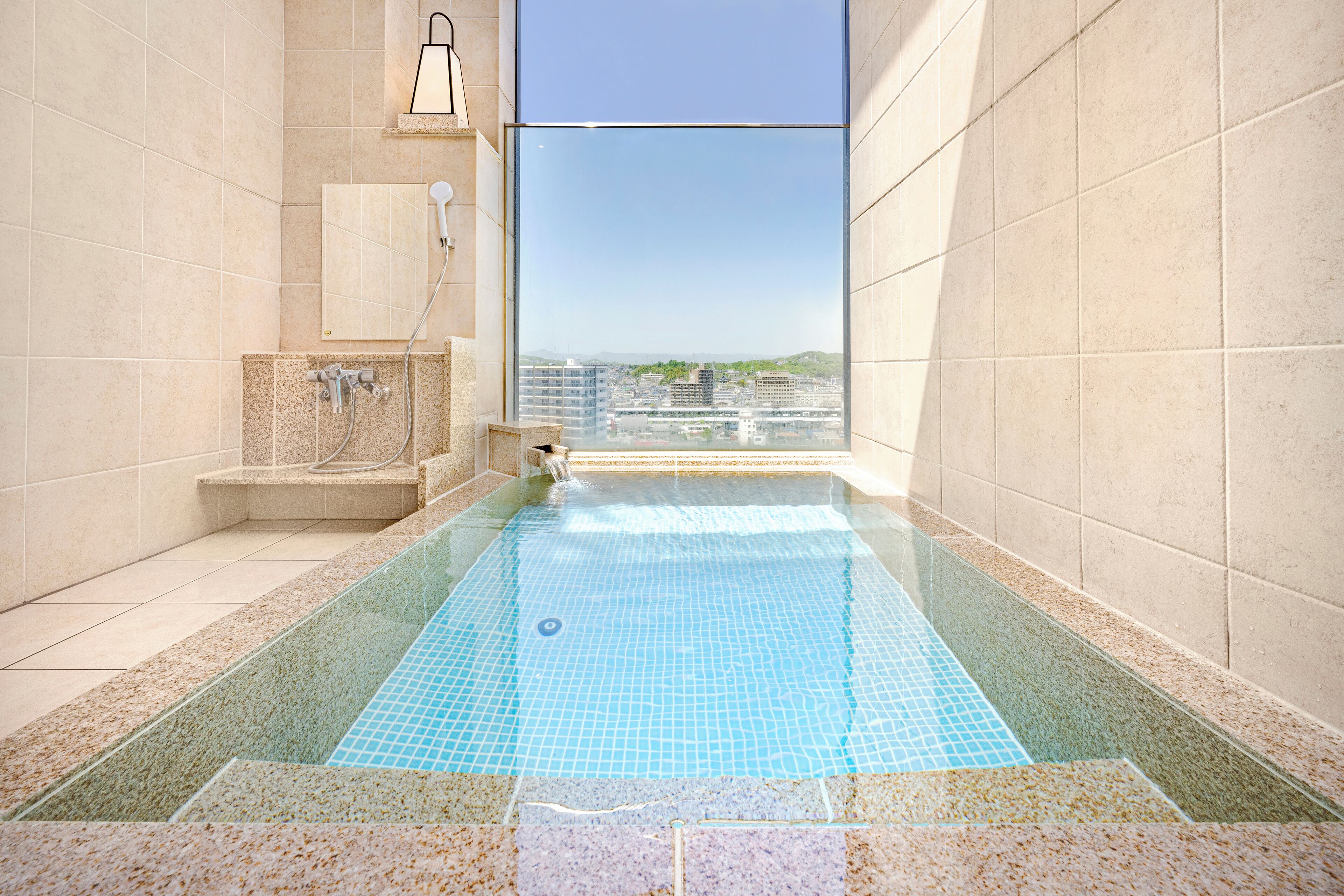 A modern bathroom with a glass-enclosed shower, a built-in bathtub, and a city view.