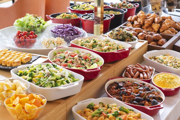 Een buffet met diverse gerechten, zoals salades, groenten en gebak.