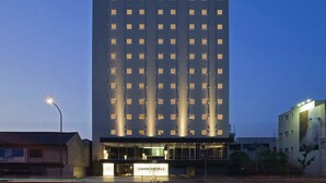 Un edificio de hotel alto con un logotipo de estrella en la parte superior, múltiples ventanas y una entrada bien iluminada.