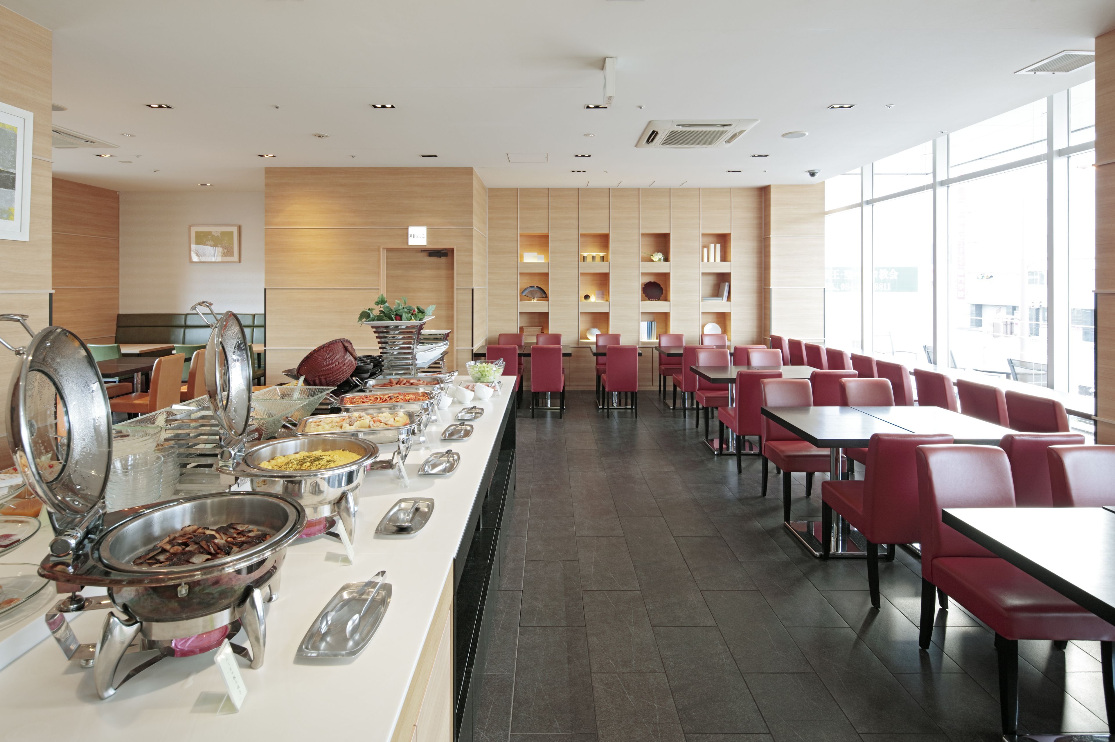 A buffet with various food items and a seating area with tables and chairs.