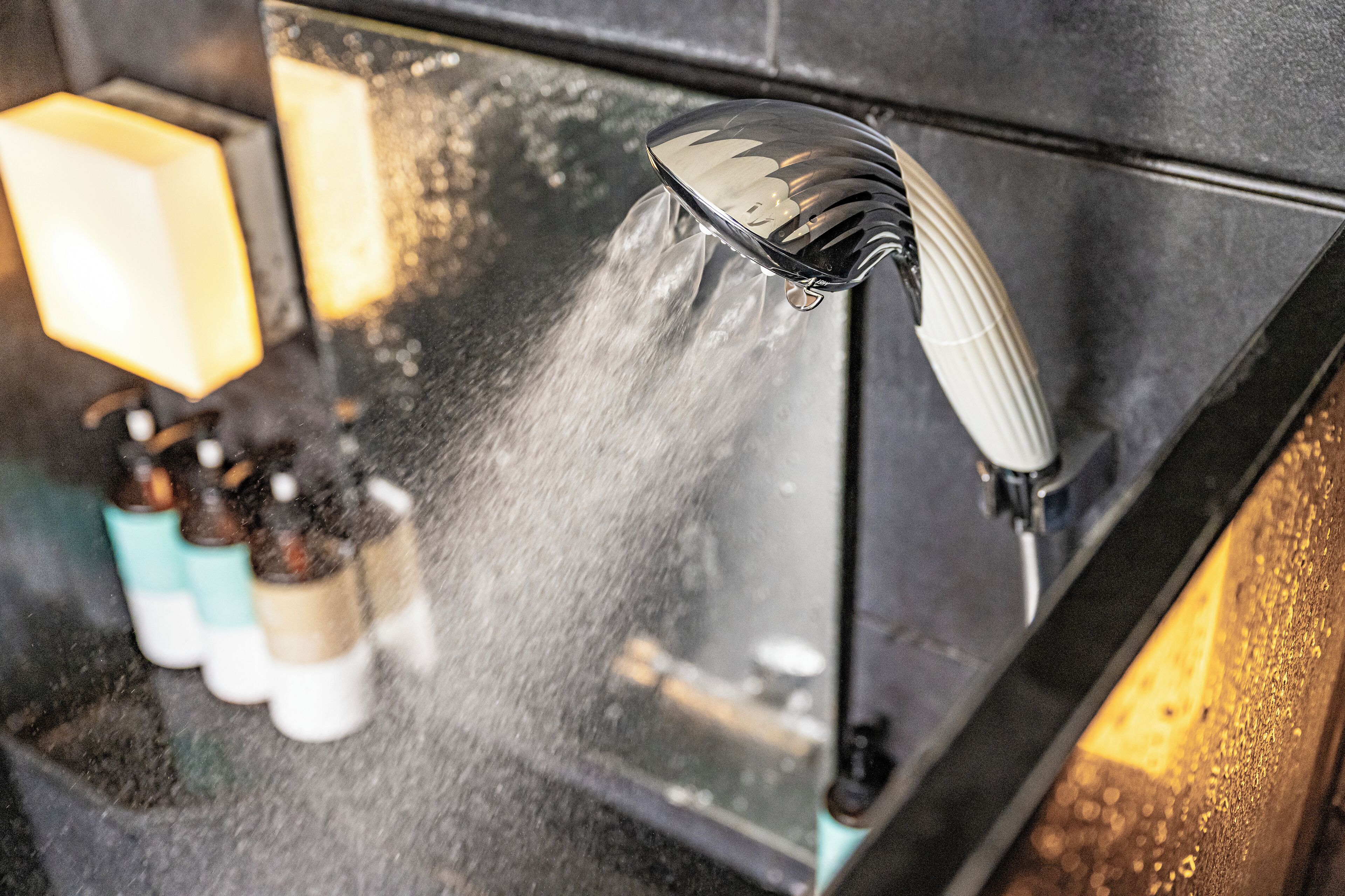 Un baño moderno con cabezal de ducha, un espejo y dispensador de jabón.