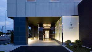 A modern hotel entrance with a glass facade, a star logo, and a well-lit reception area. - Candeo Hotels Kumamoto Airport Kikuyo (Kikuyo)