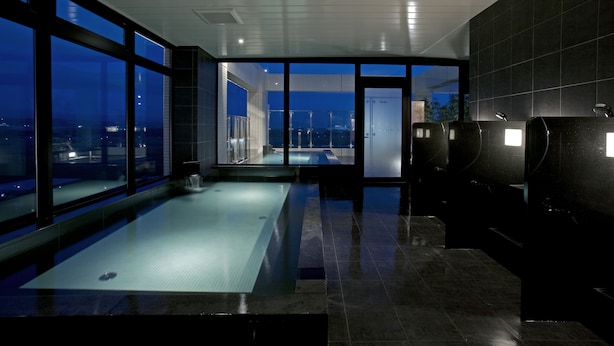 A modern indoor swimming pool with a view of the cityscape at night. - Candeo Hotels Kumamoto Airport Kikuyo (Kikuyo)