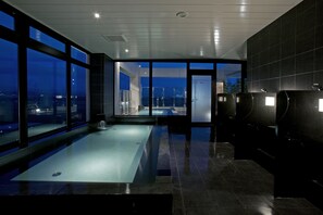 A modern indoor swimming pool with a view of the cityscape at night.