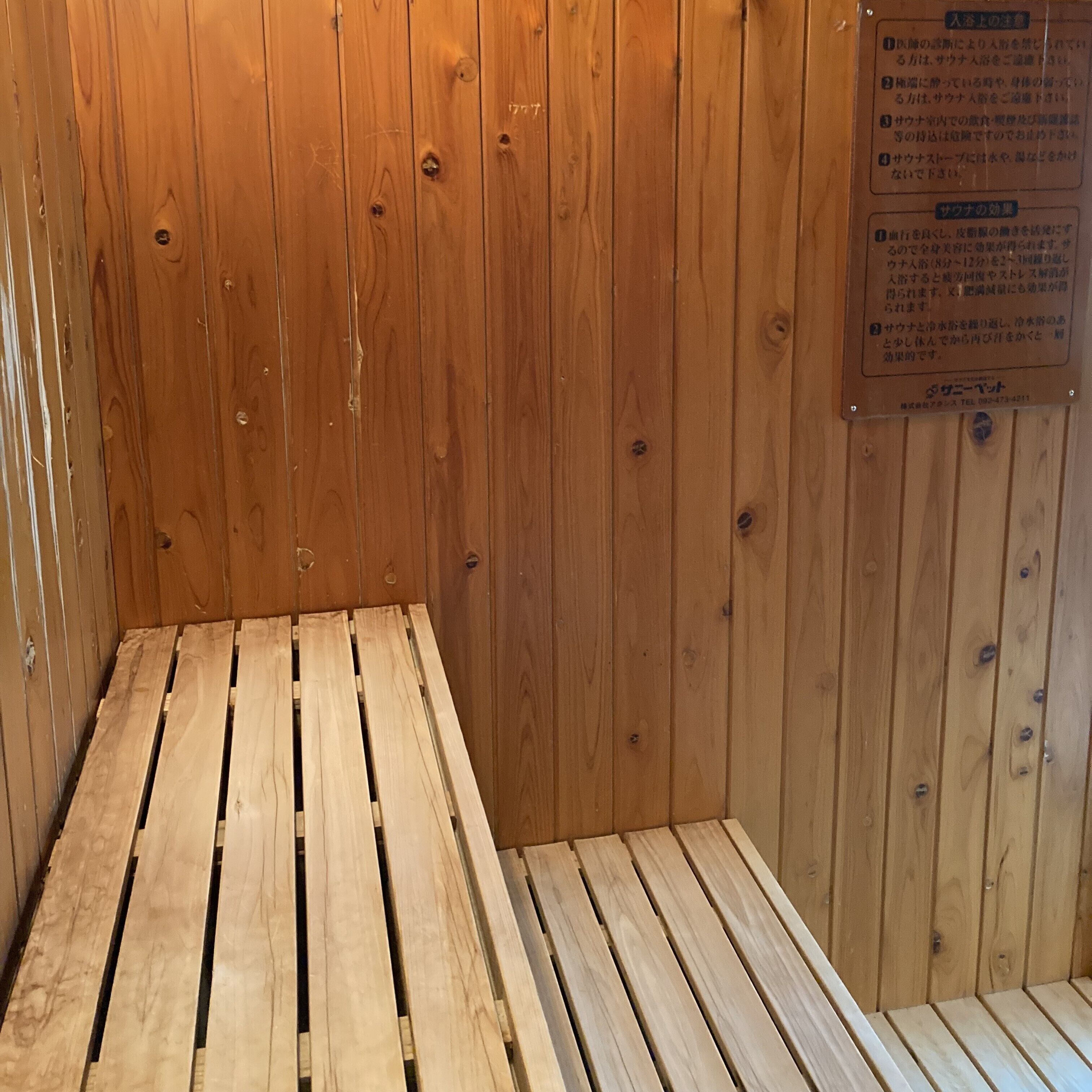 Un sauna en bois, avec un banc et une pancarte portant un texte en japonais.