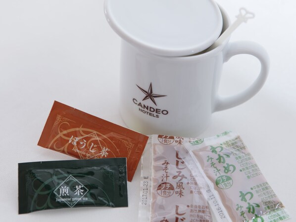 A white mug with a star logo and Japanese text, a brown packet, a black packet, and several green packets with Japanese text.