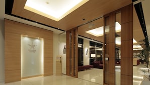 A modern hotel lobby with a wooden reception desk, a starfish decoration, and a seating area with a sofa and a lamp. - Candeo Hotels Kumamoto Airport Kikuyo (Kikuyo)