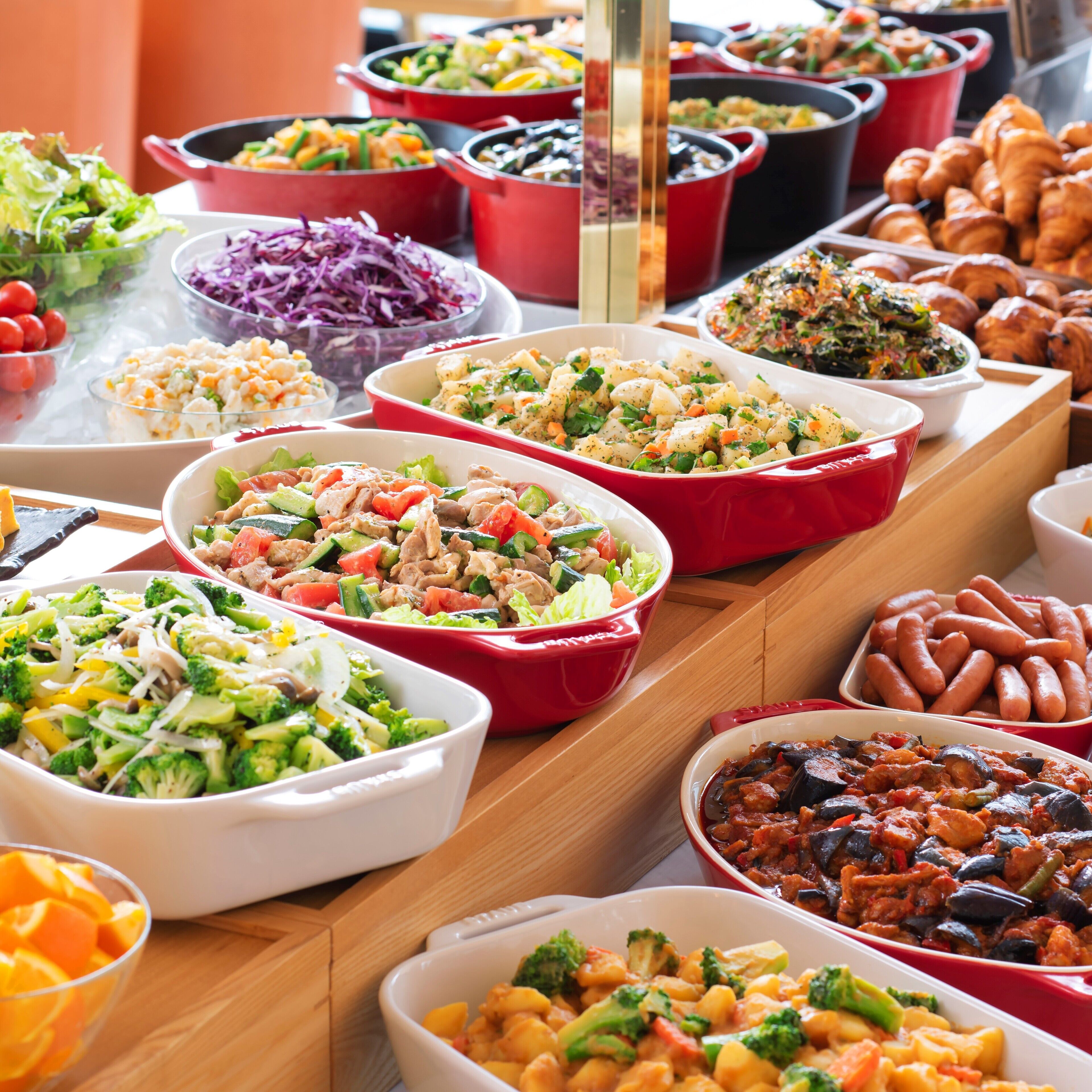 Une table de buffet proposant divers plats, notamment des salades, des pâtes et de la viande.