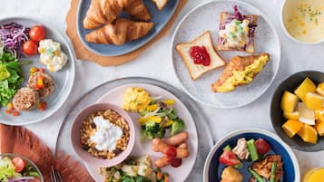 Verschiedene Frühstücksgerichte, darunter Croissants, Rührei und ein Salat.
