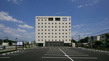 A modern hotel building with a large parking lot in front.