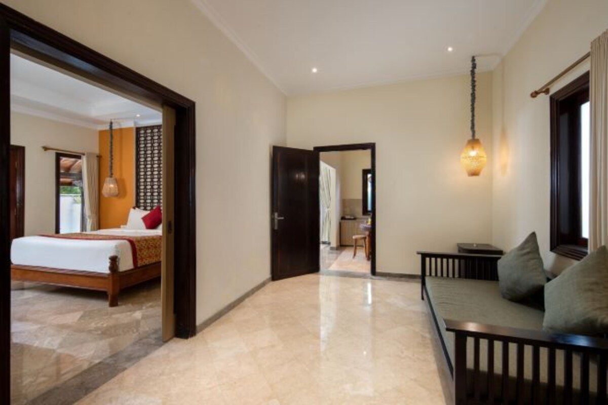 A hotel room with a bed, a sofa, a dining area, and a bathroom.
