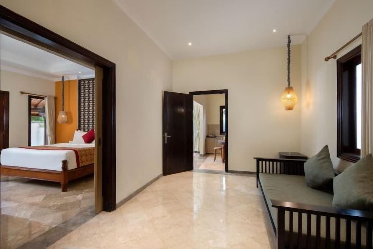 A hotel room with a bed, a sofa, a dining area, and a bathroom.