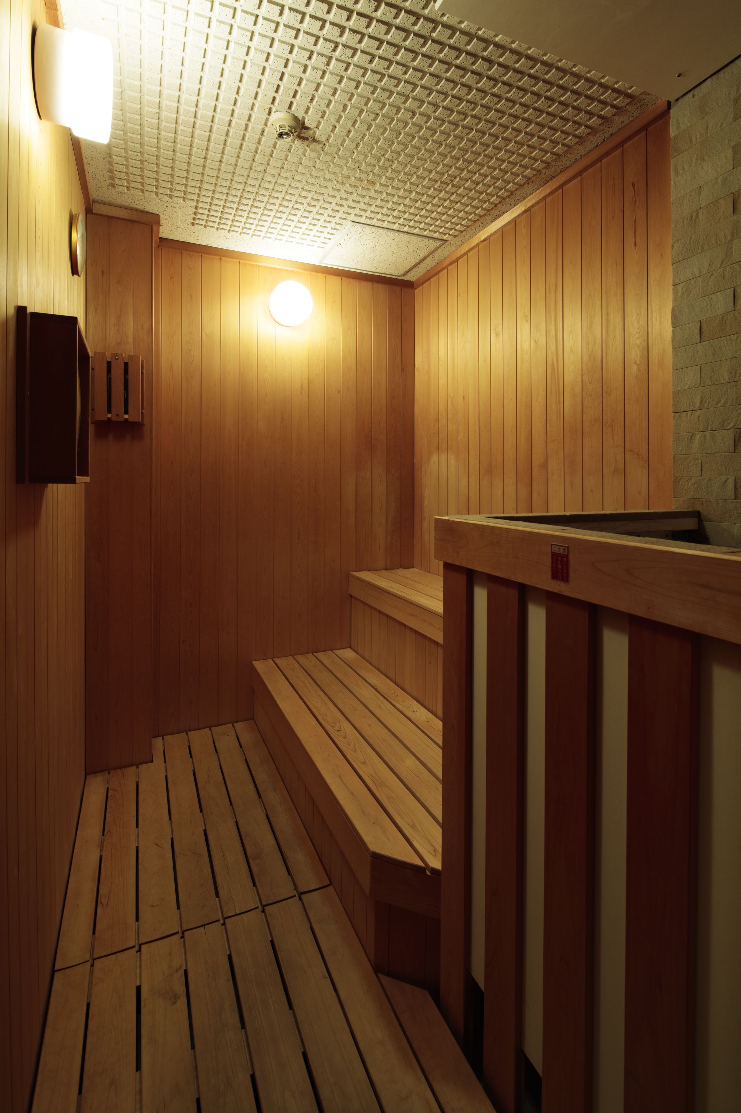 Una sauna con paredes de madera y un suelo inclinado que lleva a un banco.
