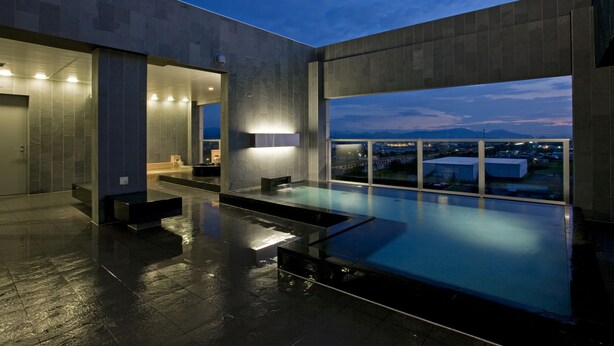 A modern indoor pool area with a view of the cityscape at dusk.