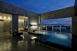 A modern indoor pool area with a view of the cityscape at dusk. - Candeo Hotels Shizuoka Shimada (Shimada)