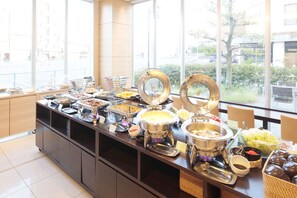 A buffet with various food items and a view of the outside through large windows.
