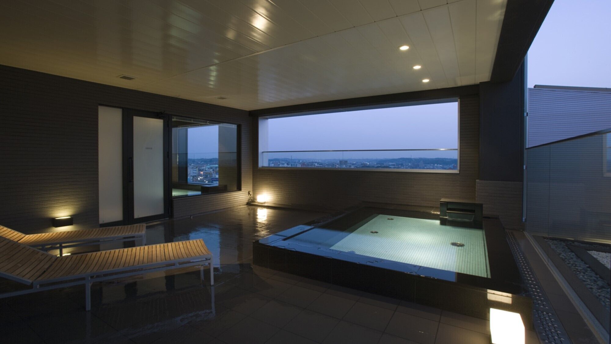 Ein moderner Wellnessraum mit großem Fenster, einer Holzbank und einer Whirlwanne.