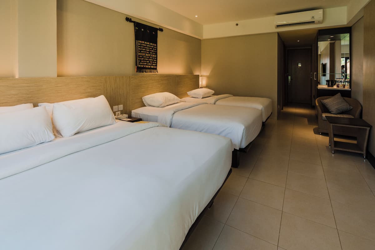 Quarto de hotel com duas camas de solteiro e um sofá.