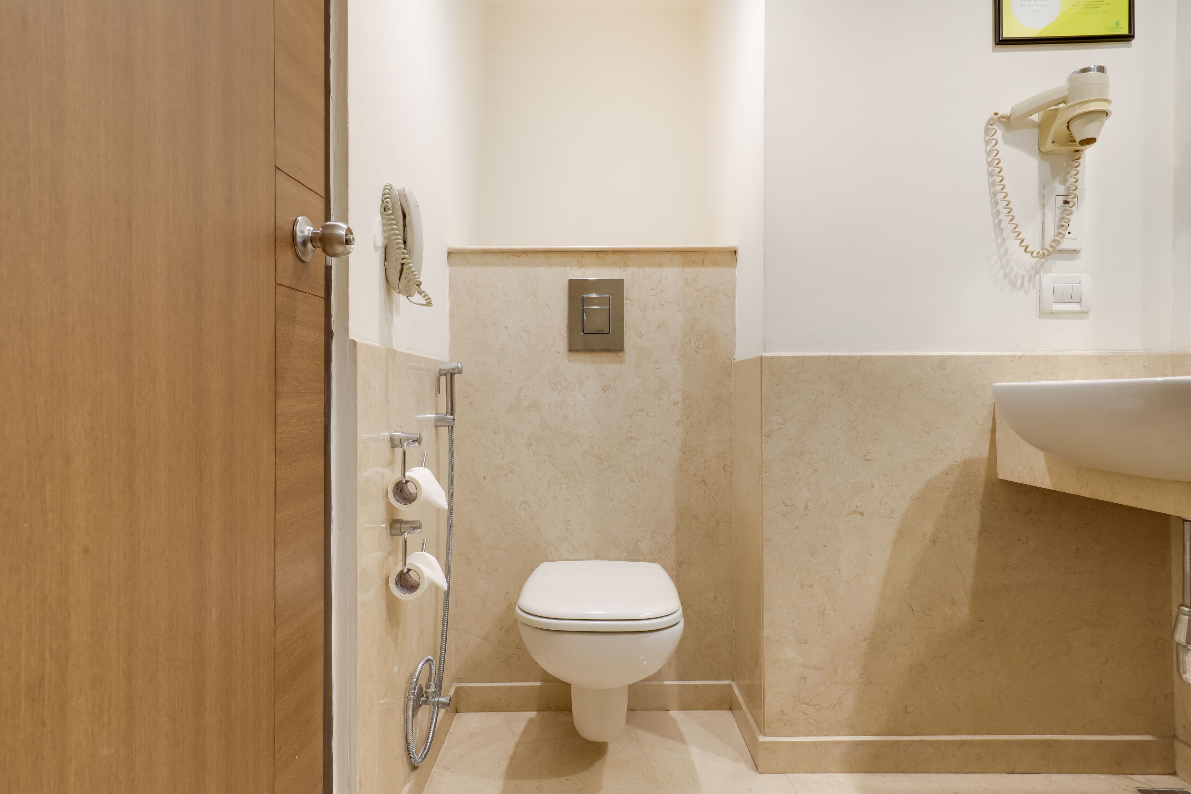 A bathroom with a toilet, a sink, a hairdryer, and a towel rack.