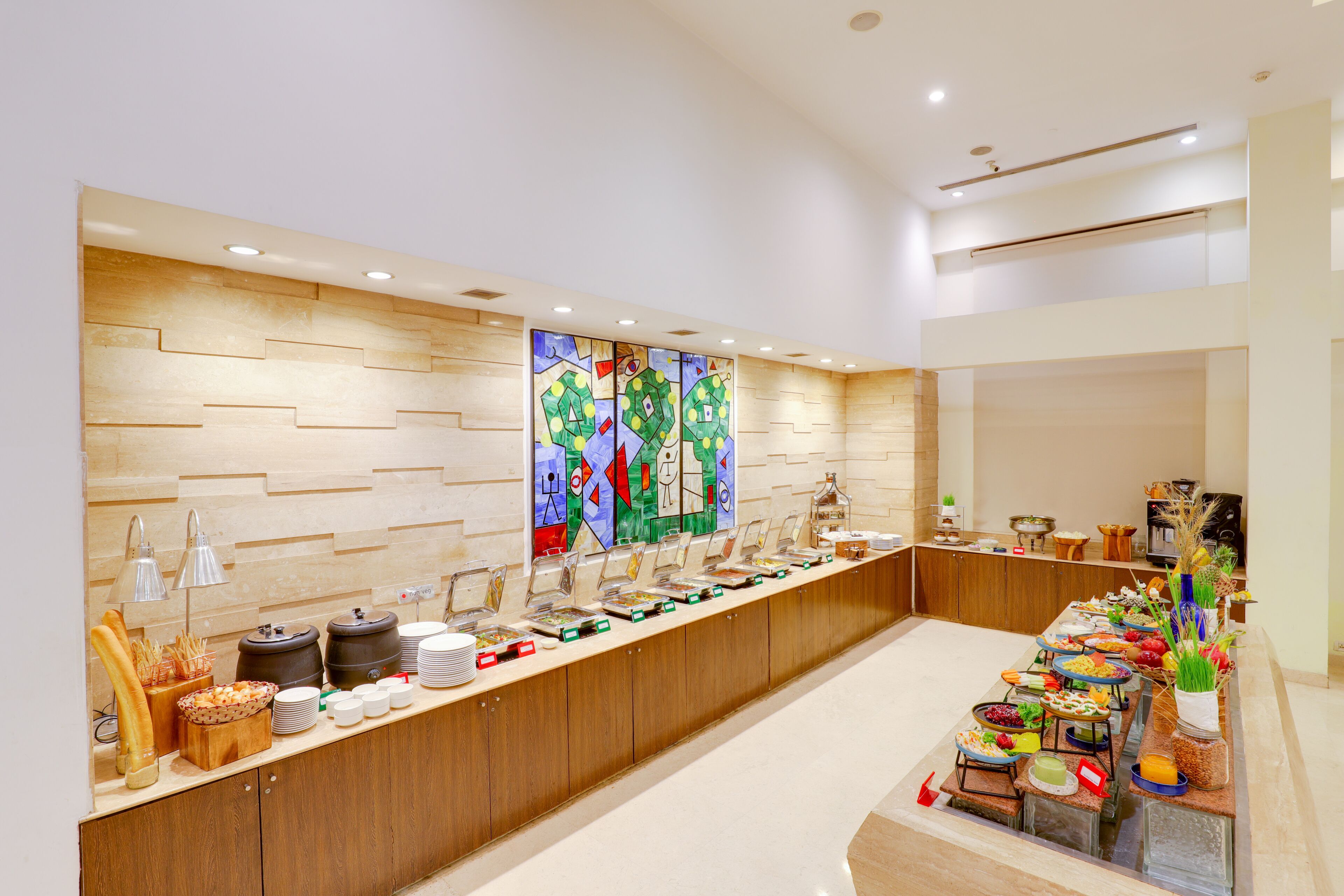 A buffet setup with various food items and a decorative wall with geometric patterns.