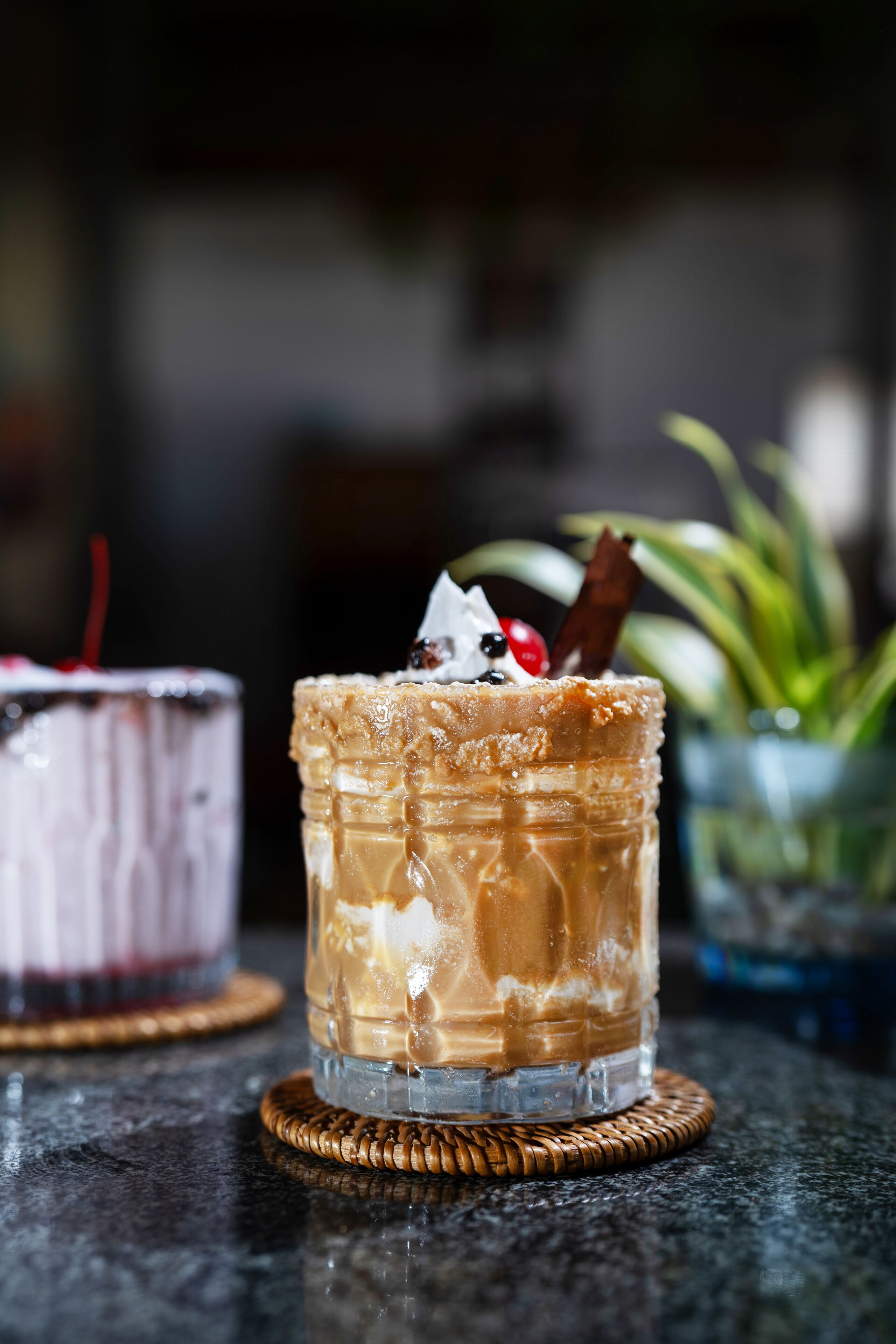 Deux verres de café glacé, garnis de crème fouettée et de chocolat, posés sur un dessous de verre.