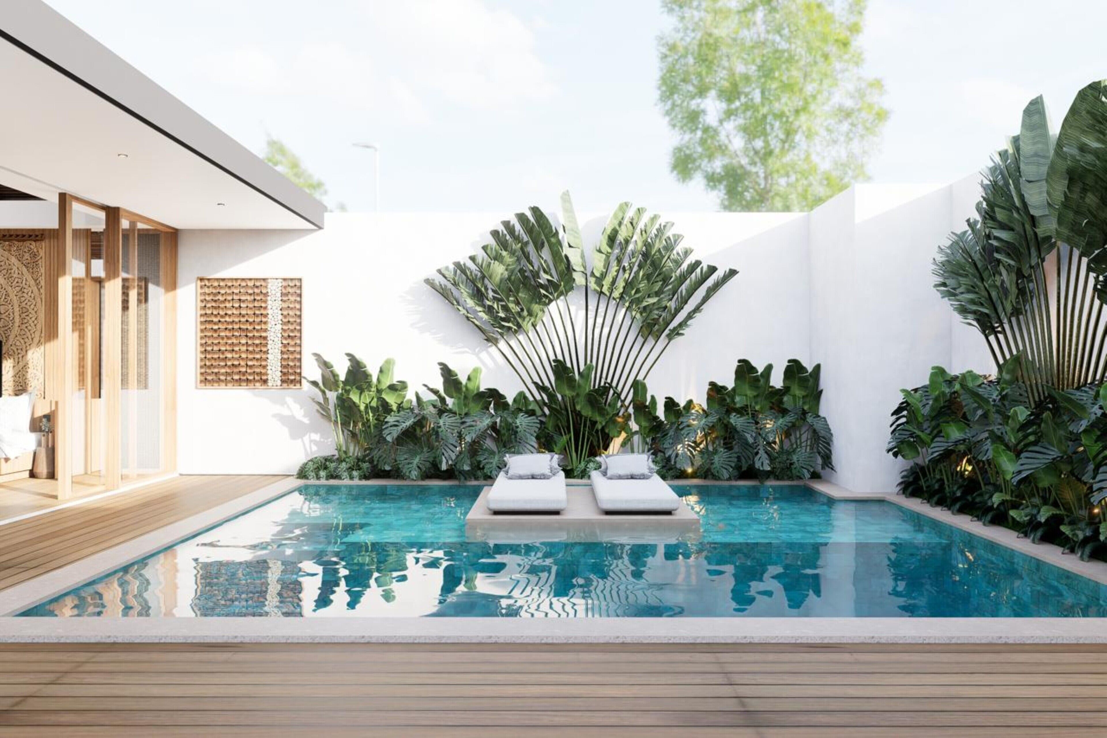 A modern outdoor pool area with two lounge chairs, surrounded by lush tropical plants and a white wall.