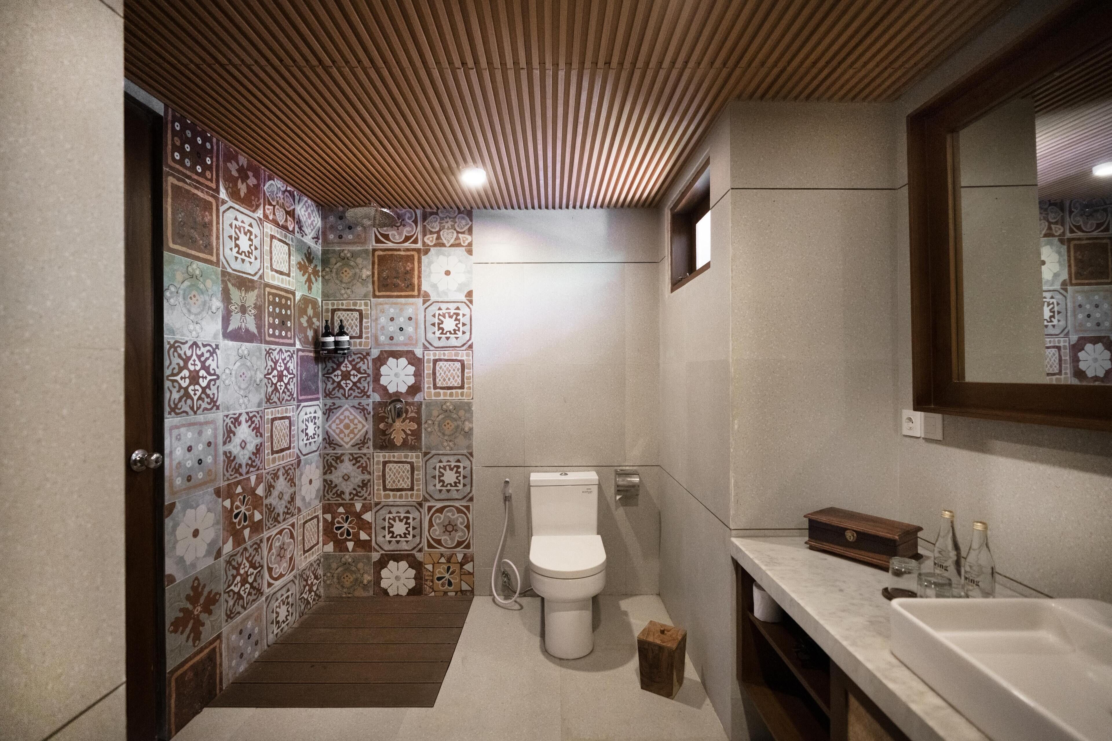 A bathroom with a tiled wall, a toilet, a sink, and a mirror.