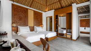 A hotel room with two beds, a dining table, and a shower area. - Nirwana Beach & Resort (Manggis)