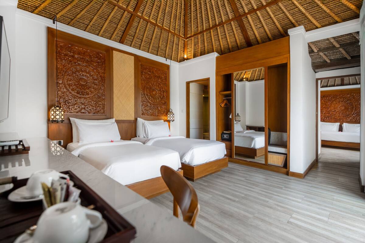 A hotel room with two beds, a dining table, and a shower area.