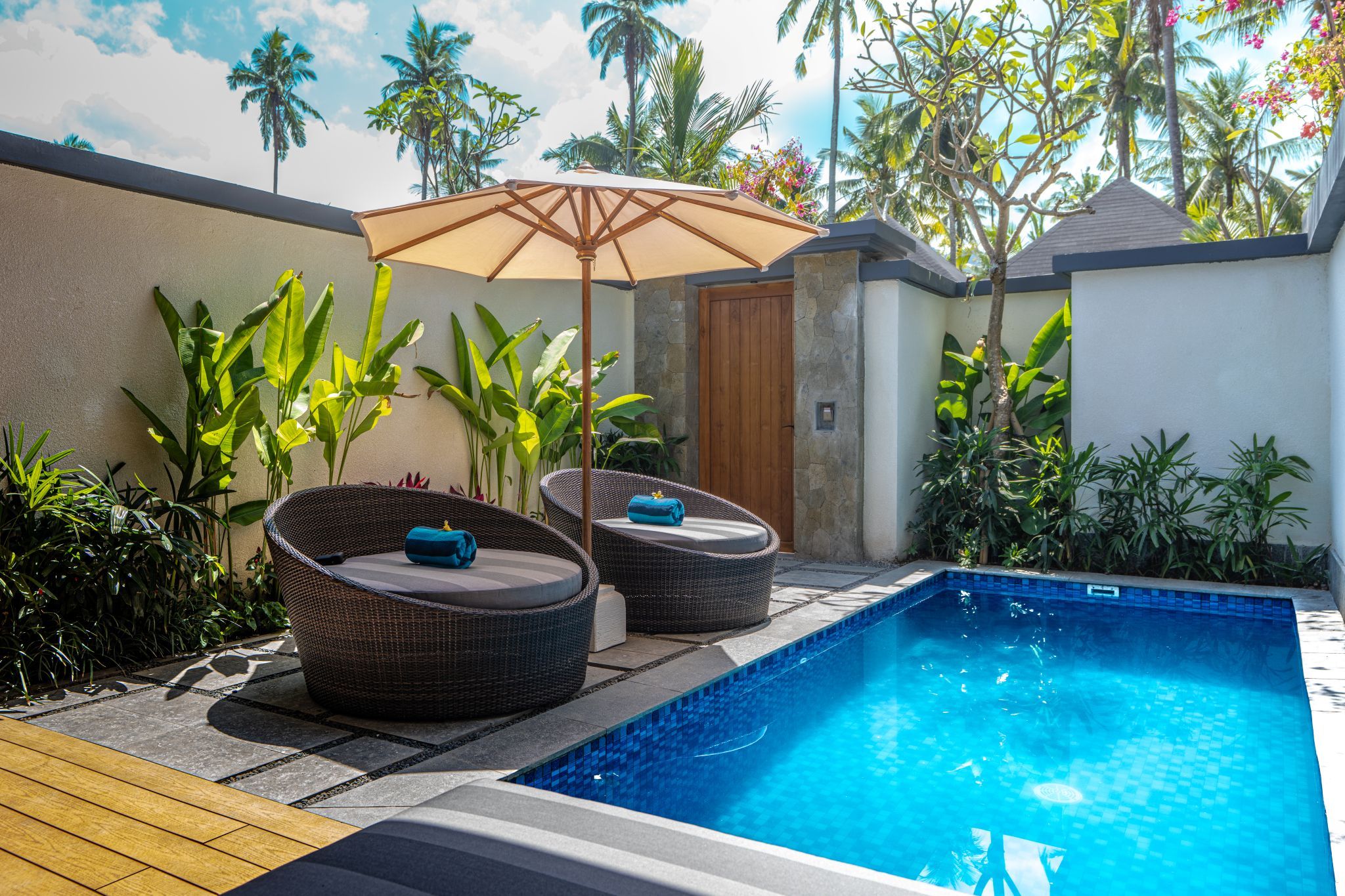 Una piscina con dos sillas de mimbre y una puerta de madera.