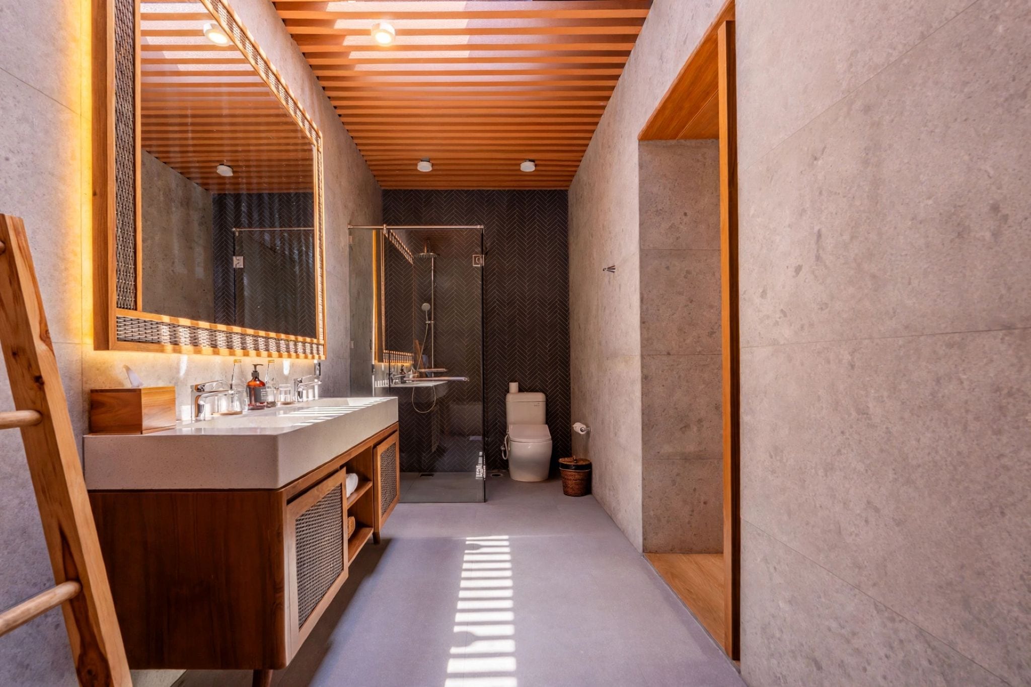 A modern bathroom with a wooden vanity, a large mirror, a shower, and a toilet.