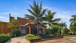 Stunning building with a central entrance, surrounded by a lush garden and a palm tree.
