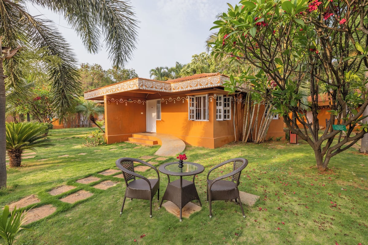 A house with a patio, a small garden, and a tree with red flowers.