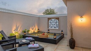 Un espacio al aire libre tranquilo para relajarse, con sillones de mimbre, una piscina pequeña e iluminación ambiental.