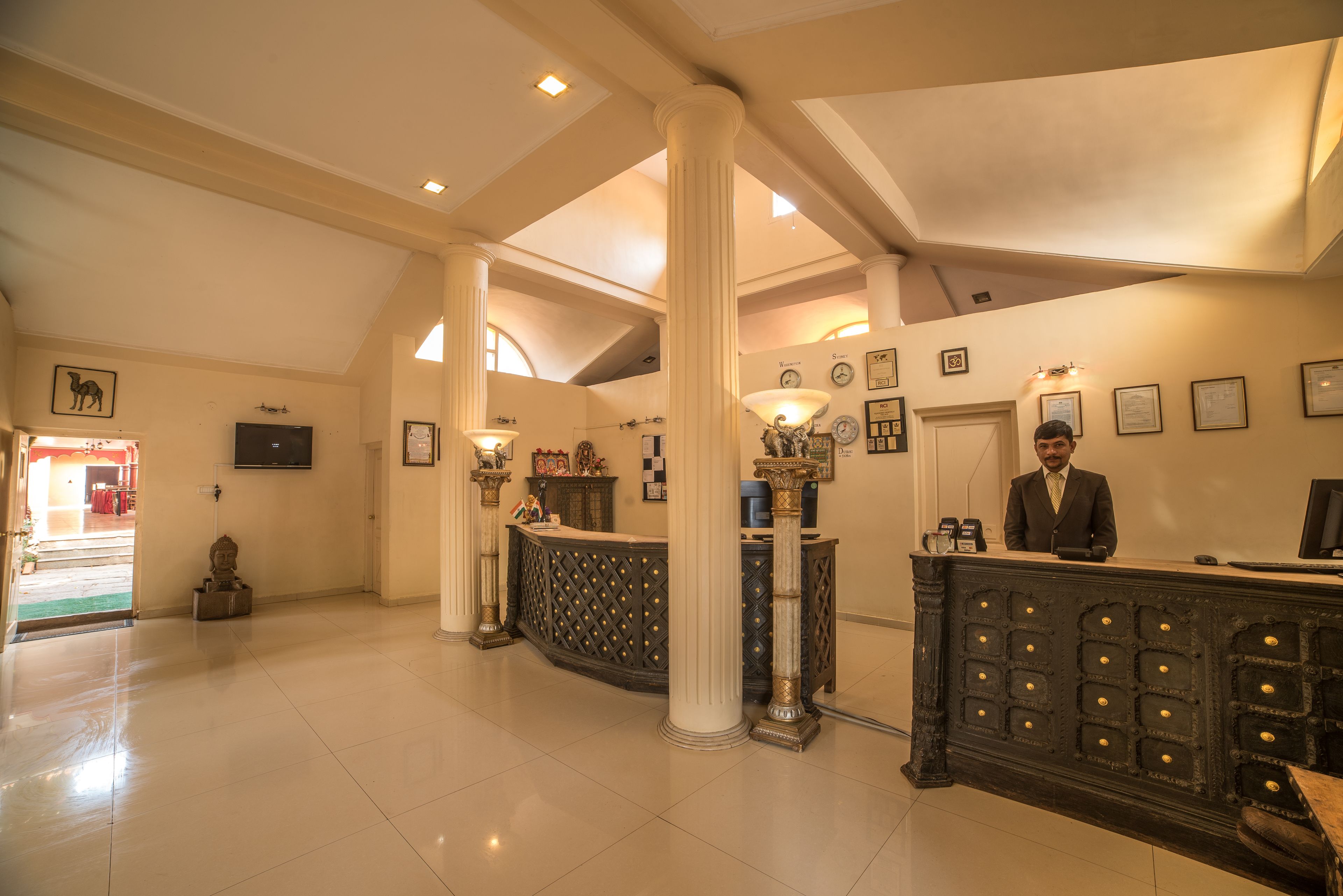 Un vestíbulo con mostrador de recepción, columnas y piso de tablones en blanco y negro.