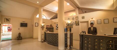 A lobby with a reception desk, columns, and a checkered floor.