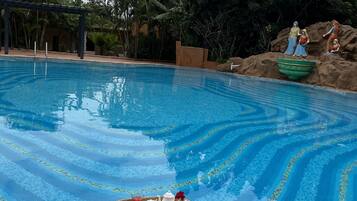 Relax by the serene pool surrounded by lush greenery and a decorative patterned edge.