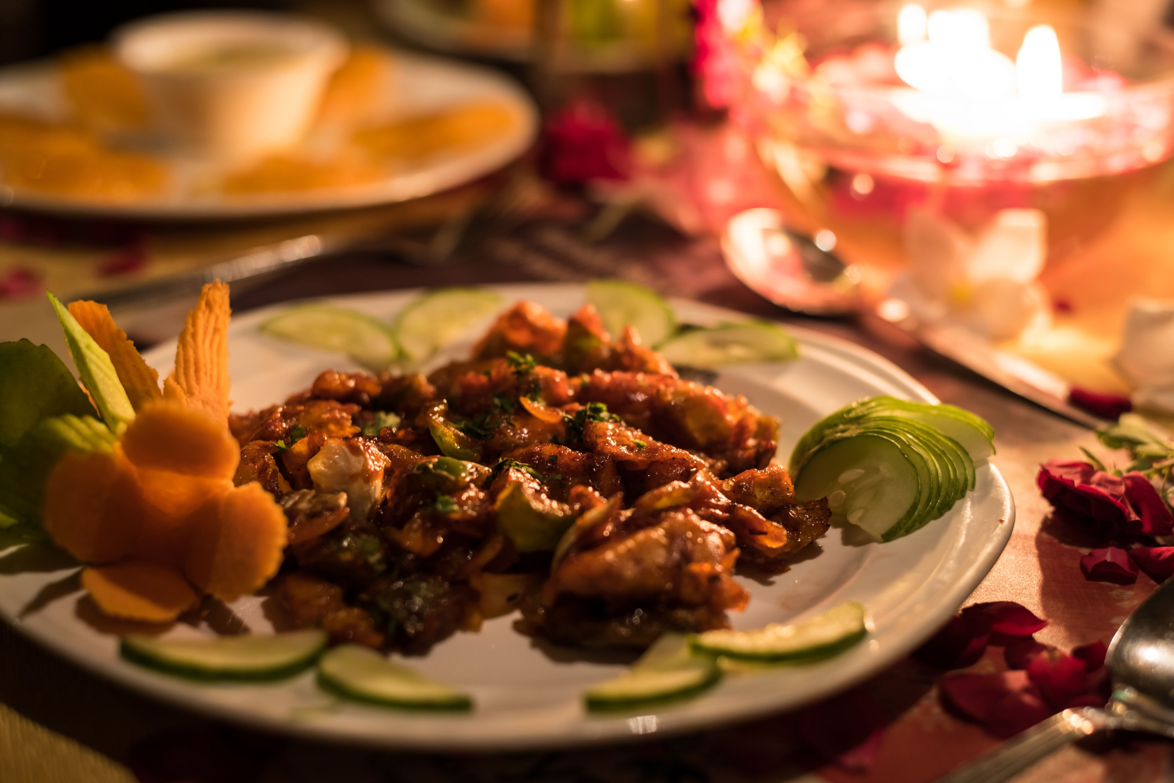 A plate of food with garnishes and a candle in the background.