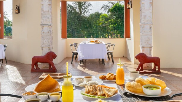 Un área de comedor al aire libre con una mesa preparada para el desayuno, que incluye varios platos y bebidas.