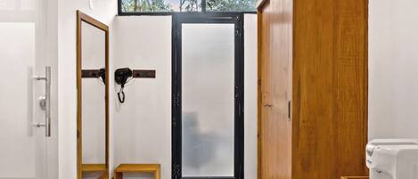 Un baño moderno con techo de madera, un espejo grande, un mueble de madera y suelo revestido de piedras.